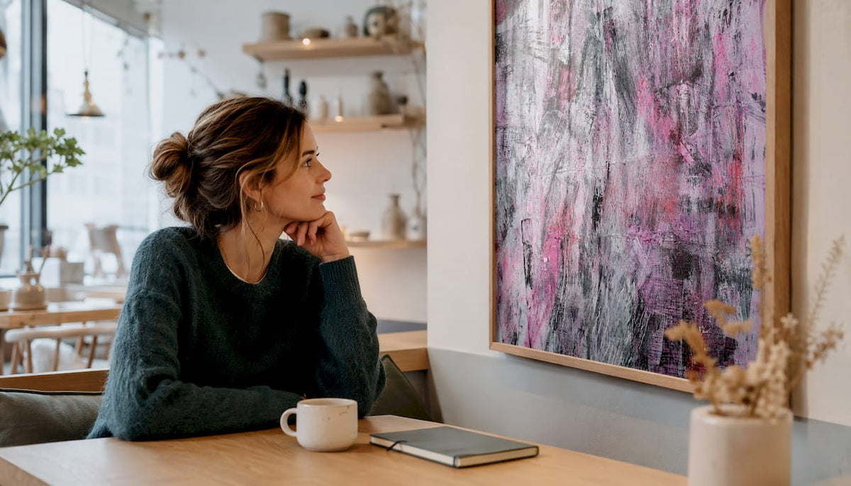 Eine Frau betrachtet ein Pastellbild mit floralen Motiven in ihrem Wohnzimmer.